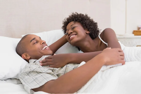 Pareja feliz acostada en la cama abrazándose — Foto de Stock