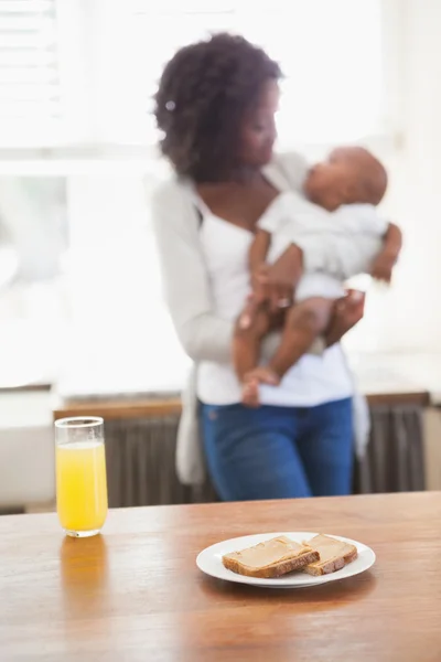 Groen in een kom op het bord met spinazie pureeευτυχισμένη μητέρα που κρατάει γιού στο πρωινό — Φωτογραφία Αρχείου