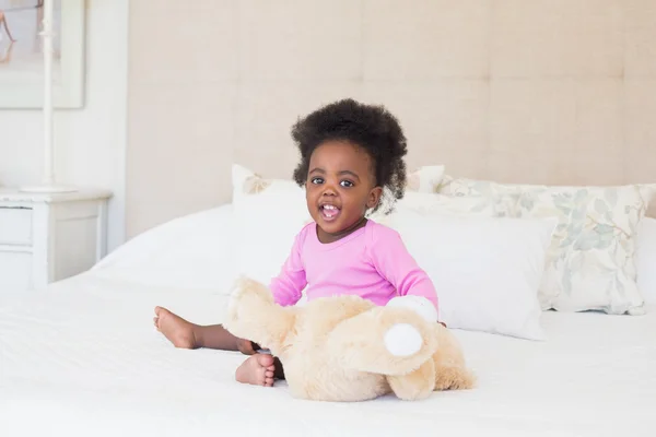 Bambina in baby gro rosa seduta sul letto — Foto Stock