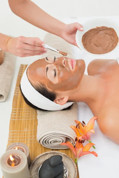 Peaceful brunette getting a mud treatment facial — Stock Photo, Image