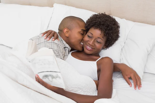 Casal feliz deitado na cama abraçando — Fotografia de Stock