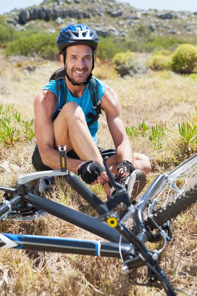 Apto ciclista amarrando seu cadarço em trilha de montanha — Fotografia de Stock