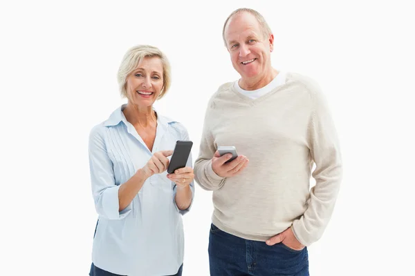 Pareja madura feliz usando sus teléfonos inteligentes — Foto de Stock