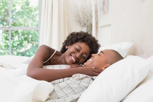 Happy couple lying in bed cuddling — Stock Photo, Image