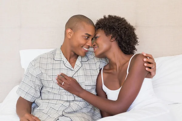 Счастливая пара, сидящая на кровати обнимаясь — стоковое фото