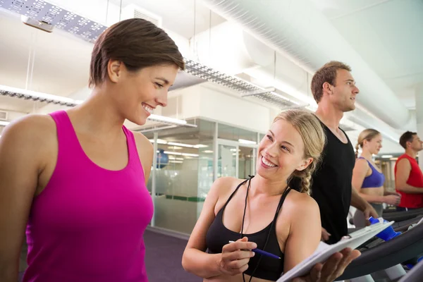 Trainer talking to her client on the treadmill — Stock Photo, Image