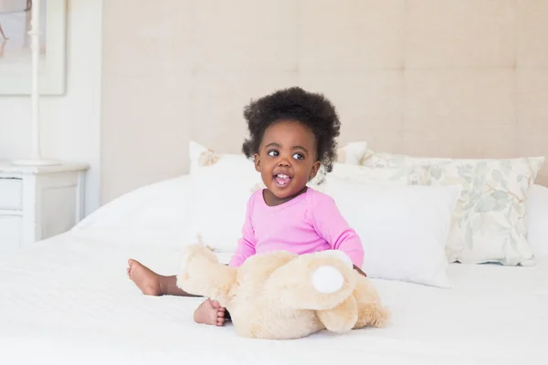 Petite fille en rose Mamagoose assis sur le lit — Stock fotografie