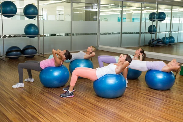 Lezione di fitness facendo sit up su palle da ginnastica in studio — Foto Stock