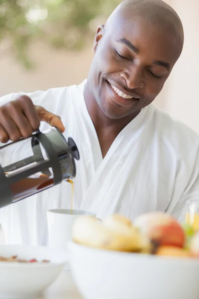 Happy man in bathrobe pouring coffee on terrace — Stock Photo, Image
