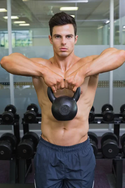 Muscular man lifting kettle bell in gym — Stock Photo, Image