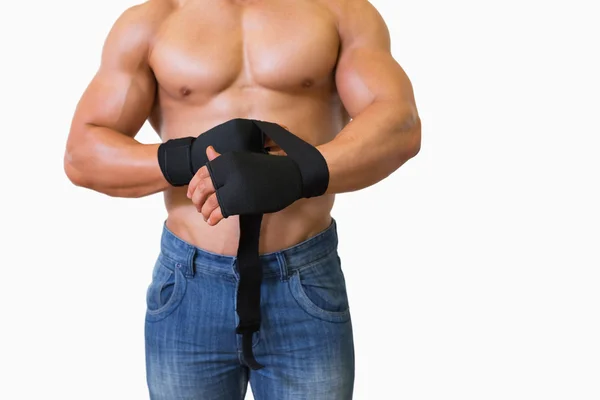 Средняя часть мускулистого человека связывает повязку на руке — стоковое фото