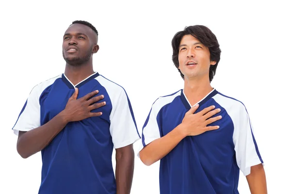 Fotbollsspelare i blått med handen på hjärtat — Stockfoto