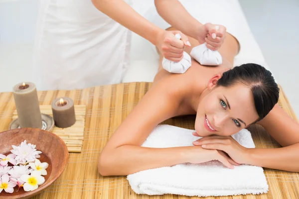 Friedliche Brünette genießt eine Kräuterkompresse Massage — Stockfoto