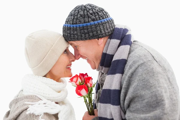 Gelukkige volwassen paar in winterkleren met rozen — Stockfoto