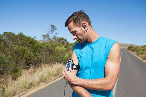 Hombre atlético ajustando su reproductor de música en una carrera — Foto de Stock