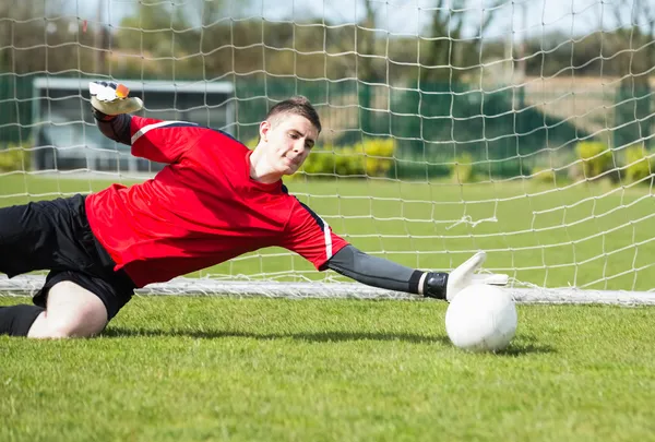 Goleiro em vermelho salvando um gol durante um jogo — Fotografia de Stock