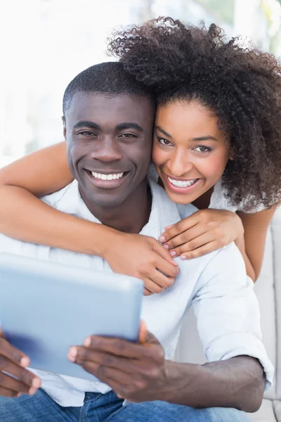 Attractive couple sitting on couch together looking at tablet — Stock Photo, Image