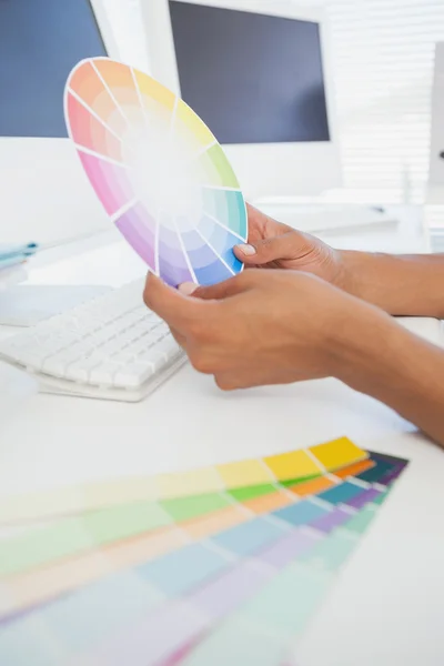Designer working at desk holding colour wheel — Stock Photo, Image