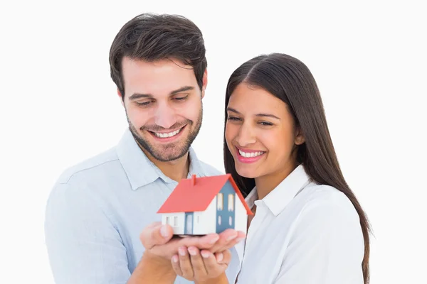 Atraente jovem casal segurando uma casa modelo — Fotografia de Stock