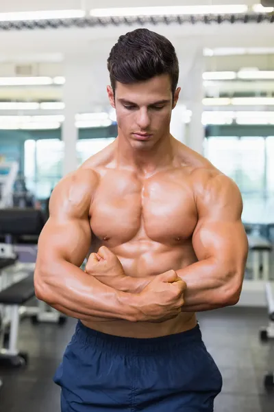 Shirtless gespierde man buigen spieren in de sportschool — Stockfoto