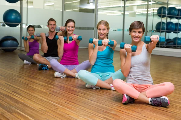 Fitness class sitting and holding dumbbells — Stock Photo, Image