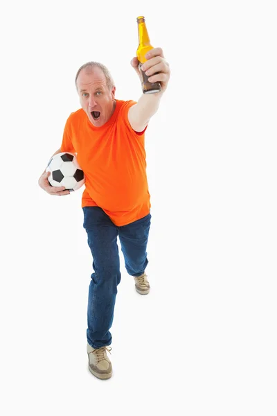 Ώριμος άνδρας σε πορτοκαλί tshirt εκμετάλλευσης της ποδοσφαίρου και μπύρα — Φωτογραφία Αρχείου