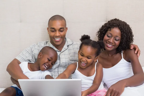 Met behulp van laptop samen op bed en gelukkige familie — Stockfoto