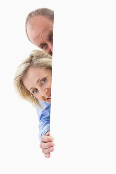 Pareja madura sonriendo detrás de la pared — Foto de Stock