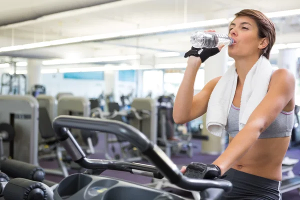 Fitte Frau trinkt auf dem Heimtrainer — Stockfoto