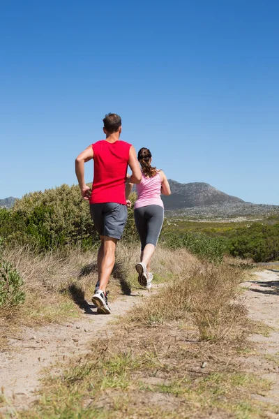 Active couple jogging on country terrain — Stock Photo, Image