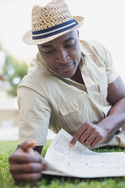 Улыбающийся человек расслабляется в своей газете для чтения в саду — стоковое фото