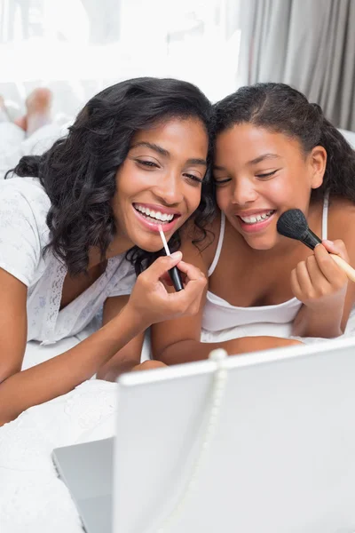 Smiling mother and daughter putting on make up — Stock Photo, Image