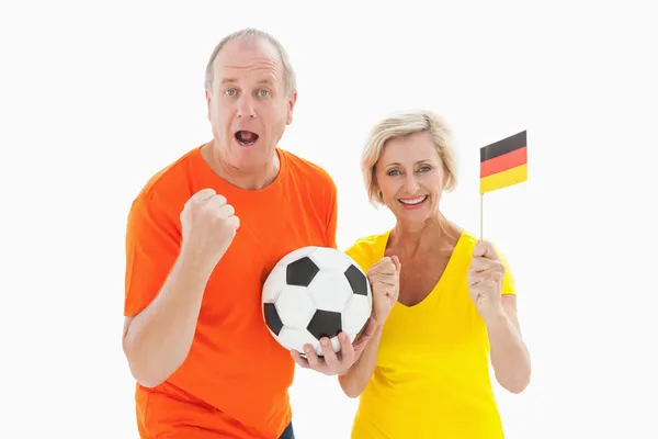 Happy german couple cheering at camera holding ball — Stock Photo, Image