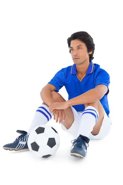 Football player in blue sitting with ball — Stock Photo, Image