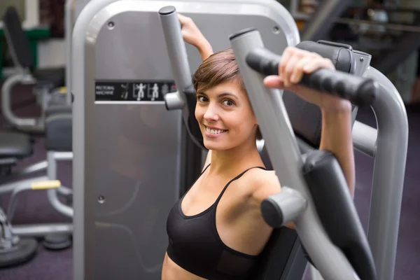 Glückliche Brünette mit Gewichten Maschine für Arme — Stockfoto