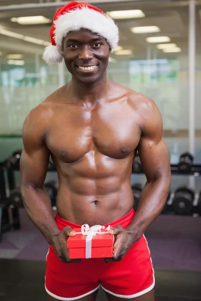 Uomo macho senza maglietta in cappello di Babbo Natale in possesso di regalo — Foto Stock