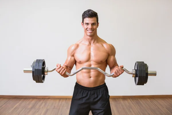 Shirtless muscular man lifting barbell in gym — Stock Photo, Image