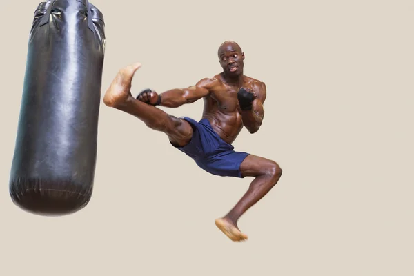 Shirtless muscular boxer kicking punching bag — Stock Photo, Image