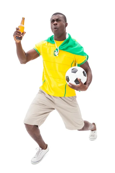 Happy brazilian football fan holding ball and beer Royalty Free Stock Photos