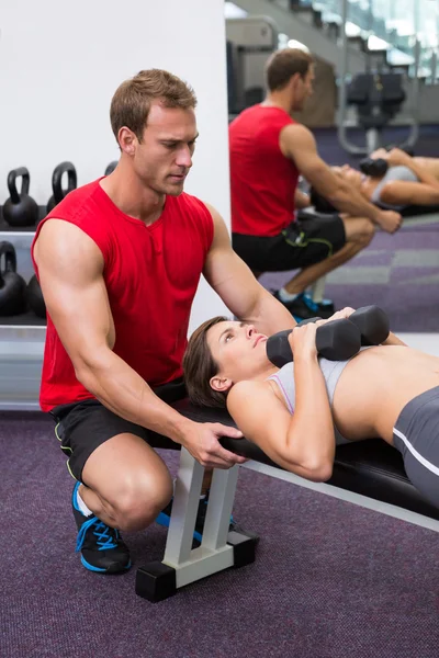 Personal trainer helping client lift dumbbells Stock Photo