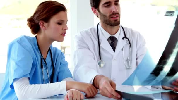 Ärzteteam schaut sich gemeinsam Röntgenbild an — Stockvideo