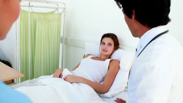 Médico y enfermera revisando al paciente enfermo en la cama — Vídeo de stock