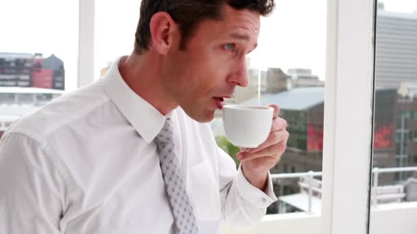 Όμορφος επιχειρηματίας πίνοντας καφέ και Κοιτώντας έξω από το παράθυρο — Αρχείο Βίντεο