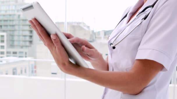 Nurse in tunic using tablet pc and smiling at camera — Stock Video