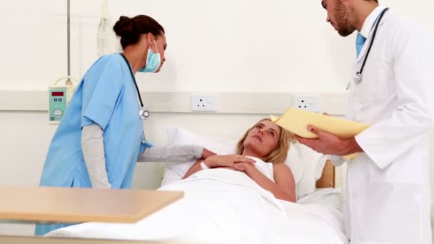 Ärzteteam überprüft kranken Patienten im Bett — Stockvideo