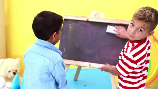 Boys wiping and knocking over mini chalkboard — Stock Video