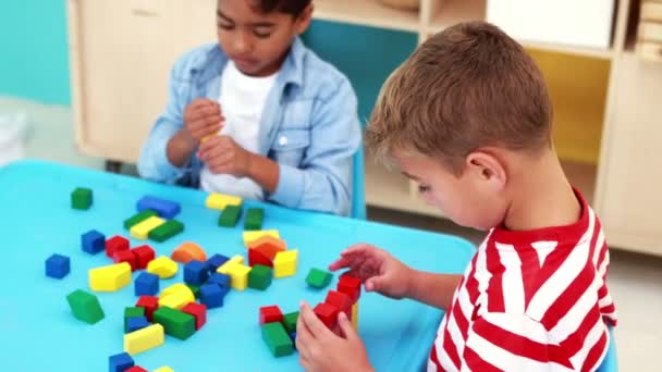 Chicos jugando con bloques de construcción en la mesa — Vídeos de Stock