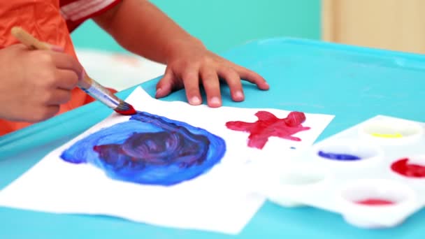 Boy painting at table in classroom — Stock Video