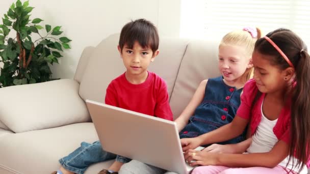 Niños usando laptop en el sofá — Vídeos de Stock