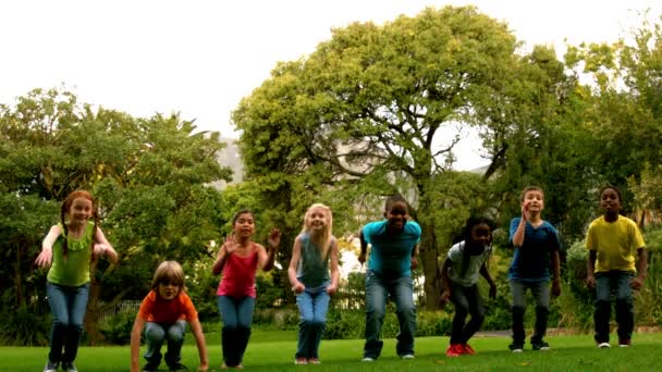 Schüler springen auf den Rasen vor der Schule — Stockvideo